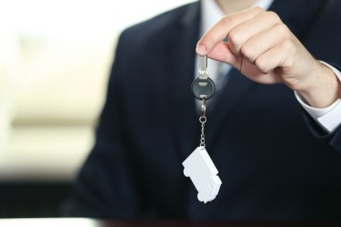 İşadamı ile anahtar taşı arka plan bulanık ofisi elinde