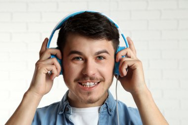 Yakışıklı genç adam tuğla duvar arka plan arka planda müzik dinlemek