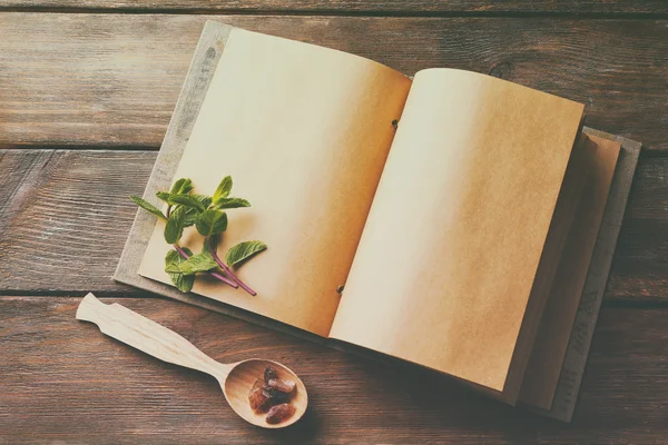 Offenes Rezeptbuch mit Minzblättern auf Holzgrund — Stockfoto