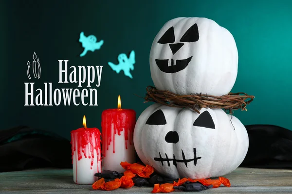 White Halloween pumpkins and candles on wooden table on dark green background — Stock Photo, Image