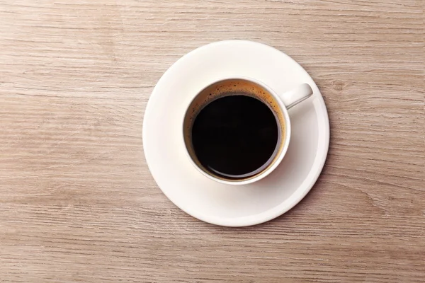 Šálek kávy na dřevěném stole, pohled shora — Stock fotografie