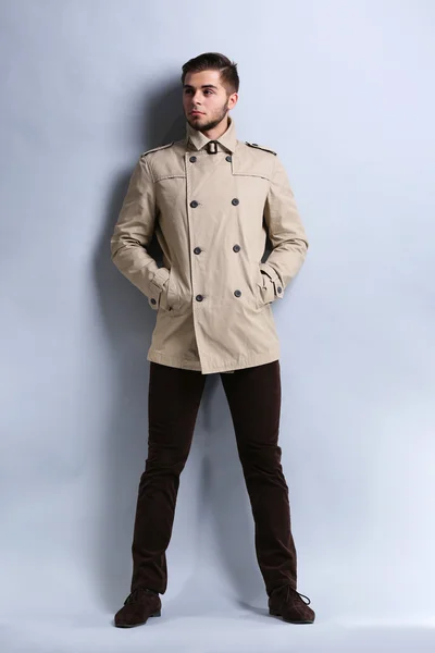 Jeune homme en manteau sur fond gris — Photo