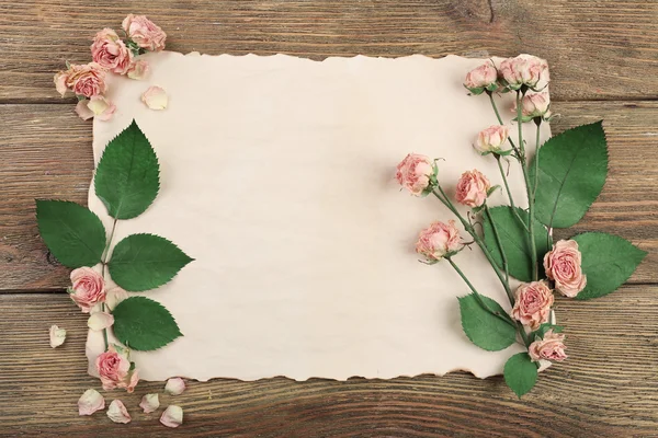 Rosas secas na folha de papel na mesa de madeira, vista superior — Fotografia de Stock