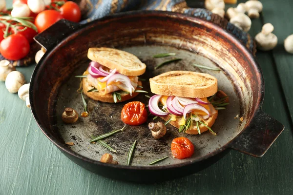 Sanduíches saborosos na panela velha, na mesa de madeira — Fotografia de Stock