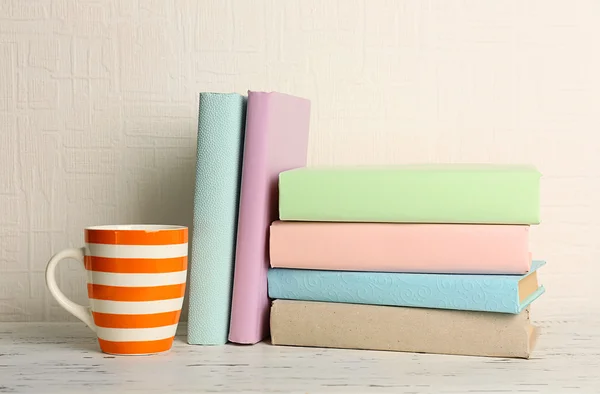 Books and cup on wooden shelf