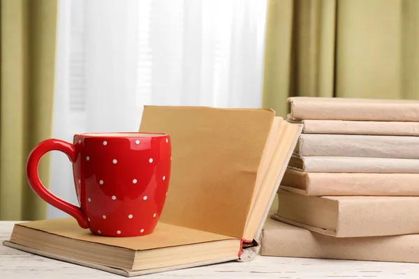 Boeken en cup op houten tafel — Stockfoto