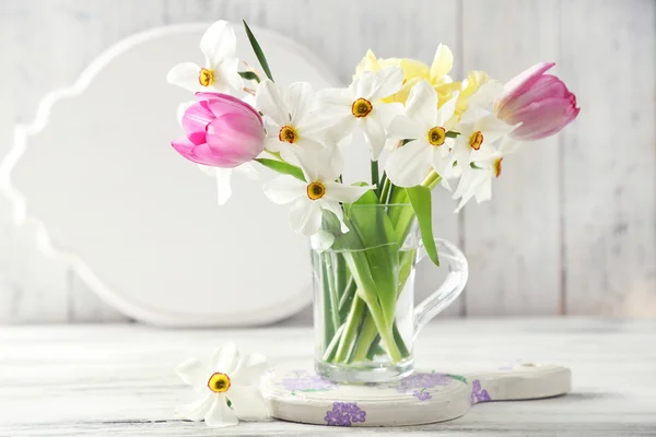 Voorjaar boeket in glazen mok op een houten achtergrond kleur — Stockfoto