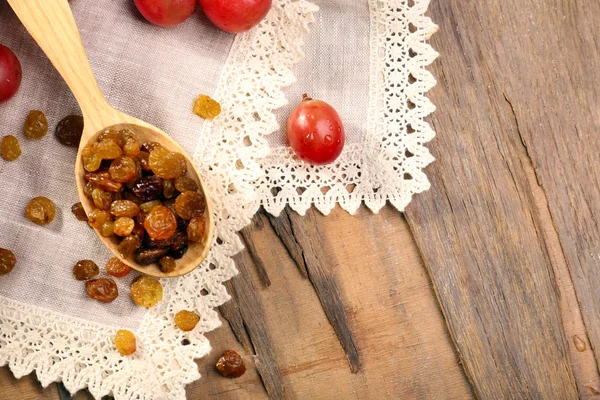 Raisins in wooden spoon with grapes — Stock Photo, Image