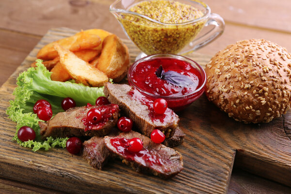 Beef with cranberry sauce, roasted potato slices and bun