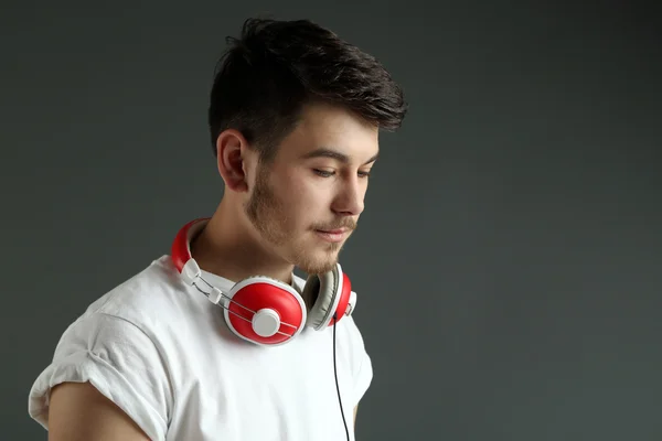 Handsome young man with headphones on grey background — Stock Photo, Image