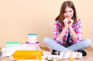 Güzel kız boyama duvar için ekipman ile katta oturan