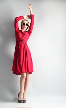 Kırmızı elbise ve gri arka plan üzerinde güneş gözlüğü ifade genç model