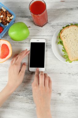 Gıda ve ahşap arka plan üzerinde eller içinde hareket eden telefon