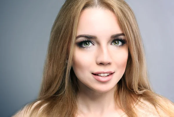 Portrait of beautiful young woman on gray background — Stock Photo, Image