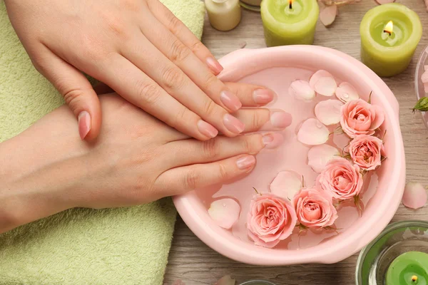 Mãos femininas com tigela de água de spa de aroma em mesa de madeira, close-up — Fotografia de Stock