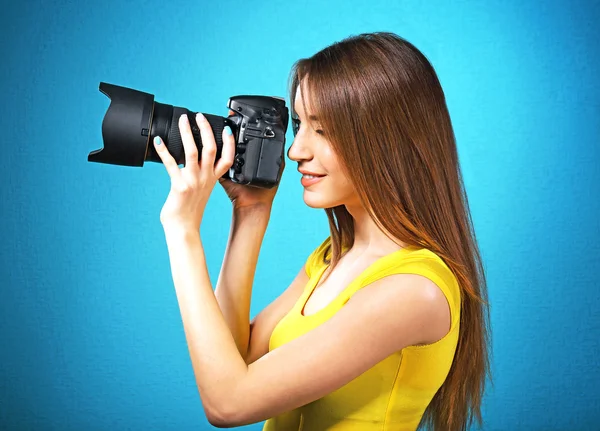 Junge Fotografin fotografiert auf blauem Hintergrund — Stockfoto