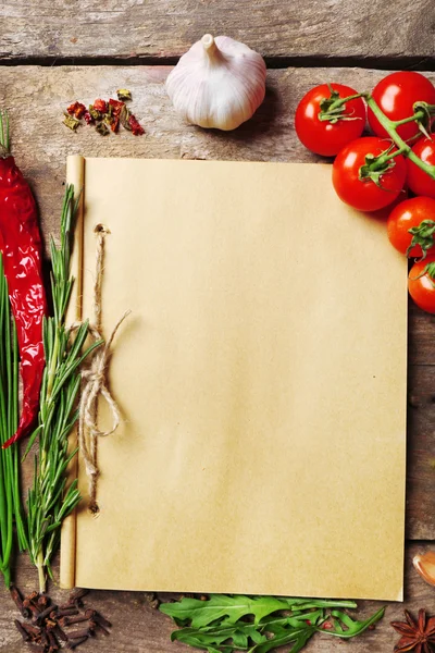 Livre de recettes ouvert avec des herbes fraîches, tomates et épices sur fond de bois — Photo