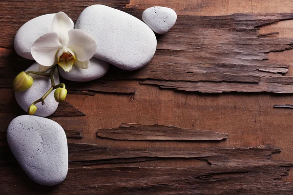 Spa stones and orchid flower on wooden background — Stock Photo, Image
