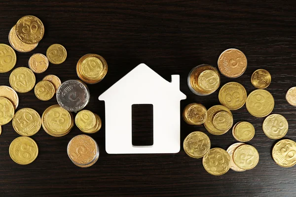 Modello di casa con monete su tavolo di legno, primo piano — Foto Stock