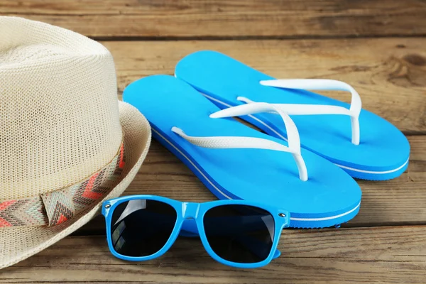 Gafas de sol, chanclas y sombrero fondo de madera — Foto de Stock