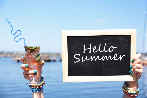 Hola concepto de verano. Pizarra en mano femenina sobre fondo de playa —  Fotos de Stock