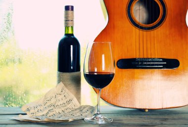 Sonraki pencere yağmur damlaları ile akustik gitar ve bardak şarap