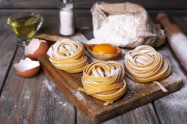 Raw homemade pasta and ingredients for pasta on wooden background — Stock Photo, Image