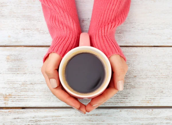 Female hands holding cup of coffee on wooden background — Stock Photo, Image