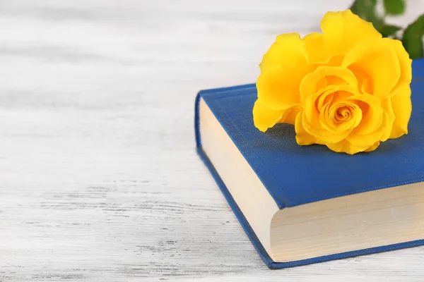 Amarelo rosa com livro sobre fundo de mesa de madeira — Fotografia de Stock