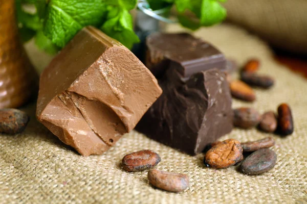 Chunks of chocolate with mint and coffee grains  on burlap cloth, closeup — ストック写真