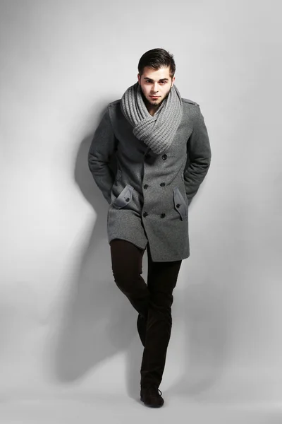 Junger Mann im Mantel auf grauem Hintergrund — Stockfoto