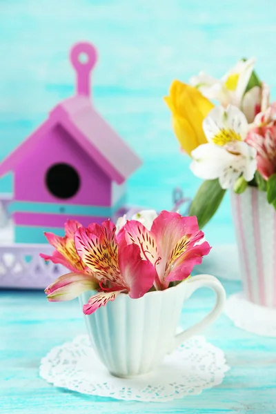 Mooie bloemen in cup, op een houten achtergrond kleur — Stockfoto