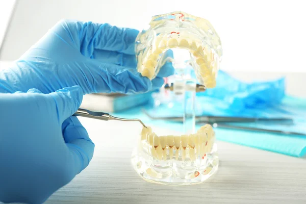 Dentes brancos falsos na mão do dentista, no fundo claro — Fotografia de Stock