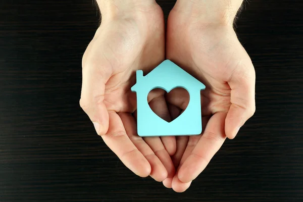 Female hands holding house on wooden background — Stock Photo, Image