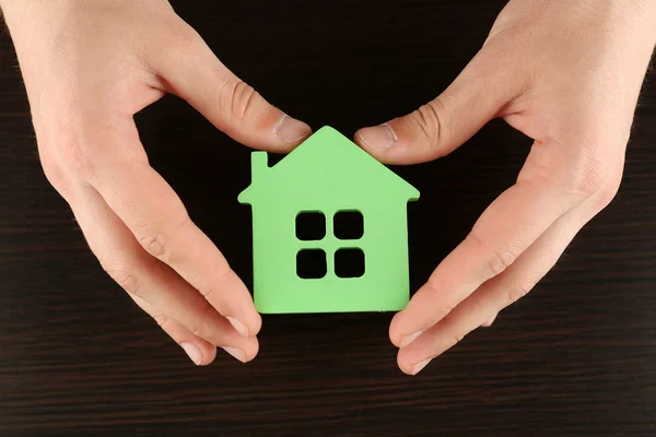 Femme mains tenant maison sur fond en bois — Photo