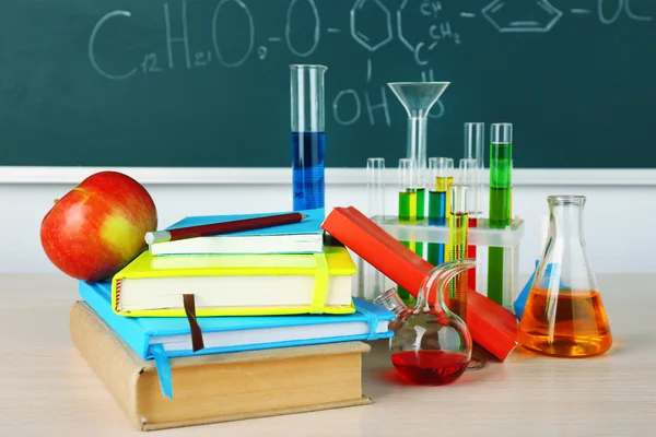 Bureau en classe de chimie avec éprouvettes sur fond de tableau noir vert — Photo