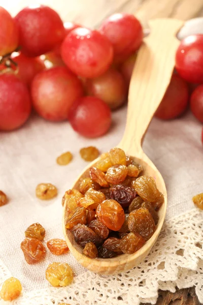 Raisins in wooden spoon with grapes on table close up — Stock Photo, Image