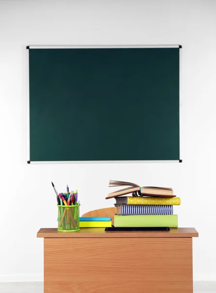 Escritorio de madera con papelería y silla en clase sobre fondo pizarra —  Fotos de Stock