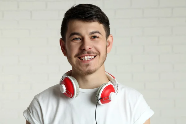 Beau jeune homme avec écouteurs sur fond de mur de briques — Photo