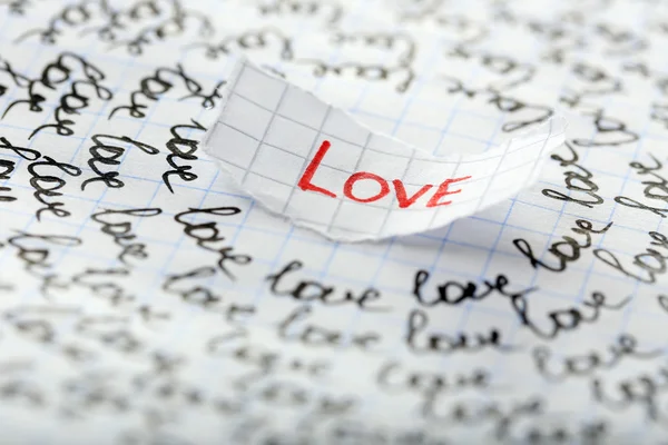 Word LOVE written on torn paper on sheet of paper background — Stock Photo, Image