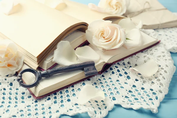 Свежие розы со старой книгой и буквами на фоне цветного деревянного стола. Винтажная концепция — стоковое фото