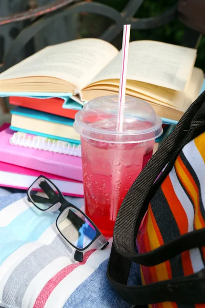 Könyvek, szemüveg, ital és a kültéri pad táska — Stock Fotó