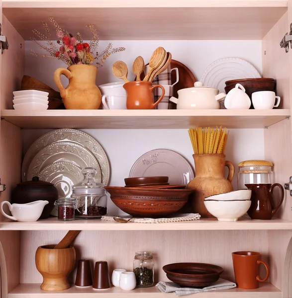 Utensilios de cocina y vajilla en estantes de madera — Foto de Stock