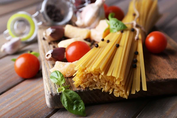 Pastas crudas con queso y verduras sobre fondo de madera —  Fotos de Stock