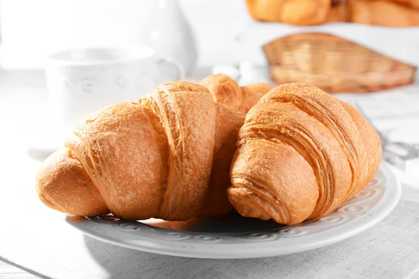 Deliciosos croissants na placa na mesa close-up — Fotografia de Stock