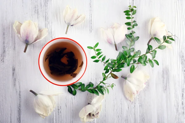 Kopje thee met mooie bloemen op houten achtergrond — Stockfoto