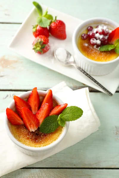 Creme Brulee Dessert mit frischen Erdbeeren auf Serviette, auf farbigem Holzhintergrund — Stockfoto
