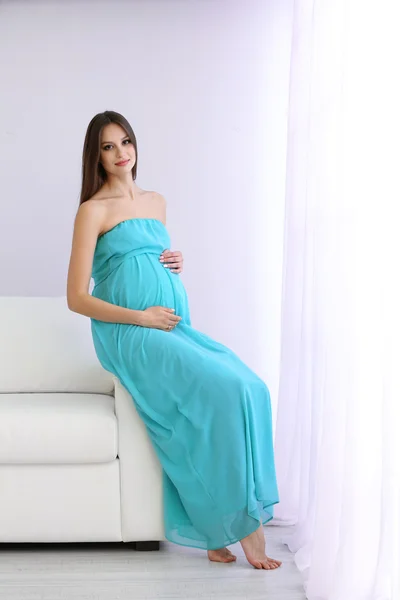 Femme enceinte assise sur le canapé dans la chambre — Photo