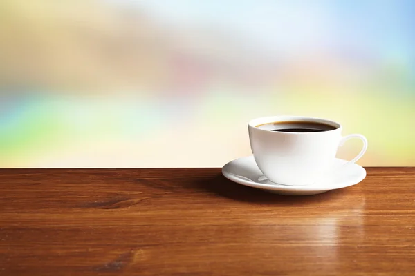 Taza de café en la mesa sobre fondo brillante — Foto de Stock