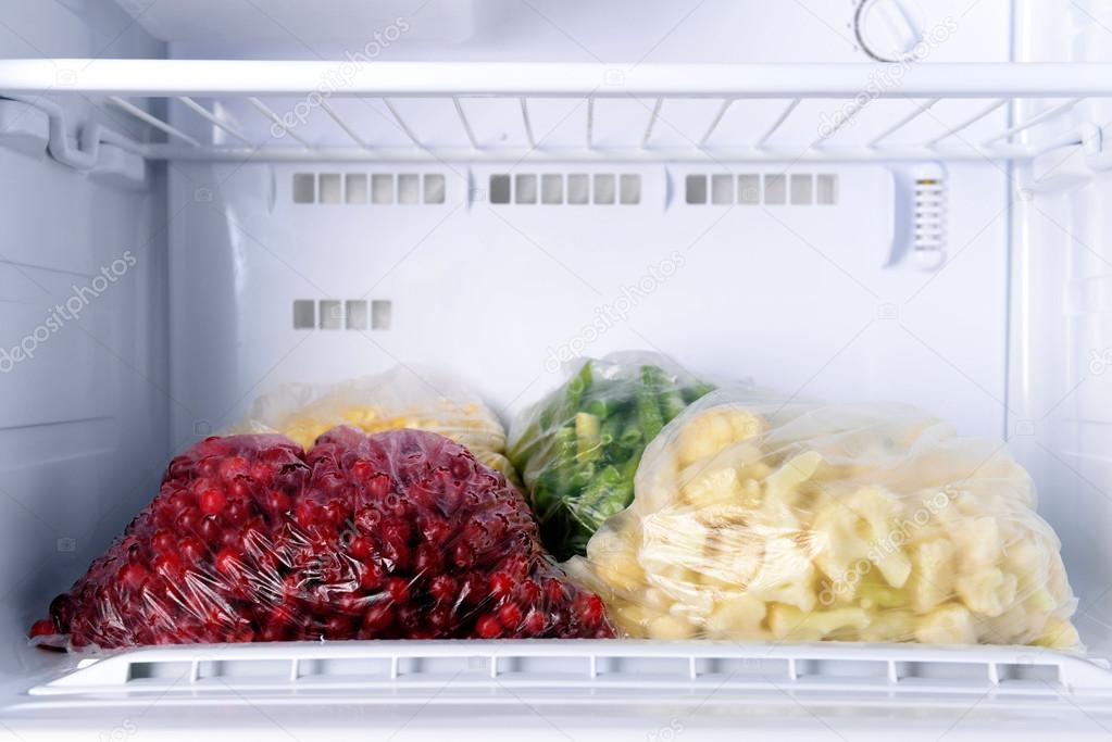 Frozen berries and vegetables in bags in freezer close up